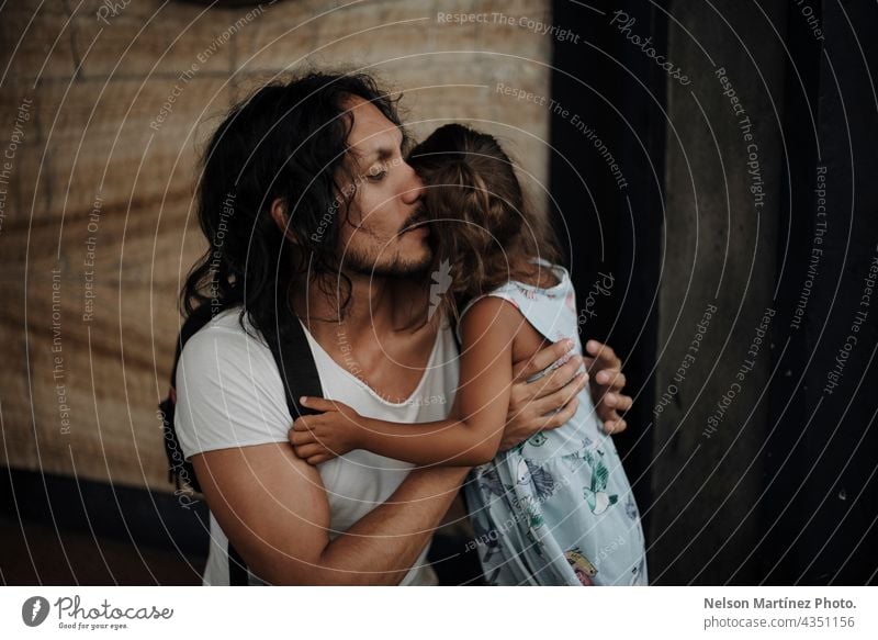 Father with long black hair hugging his daughter hispanic latin portrait family father dad childhood girl female long hair together love parent man lifestyle