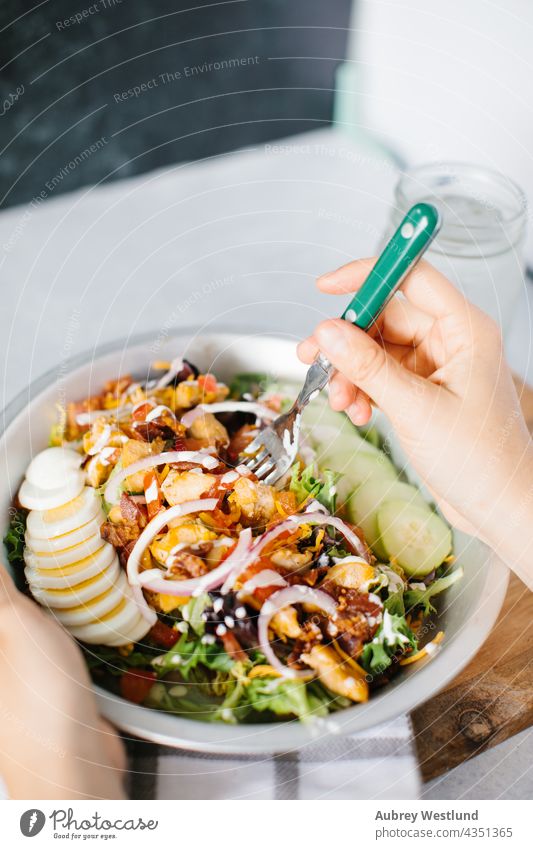 person eating cobb salad with a fork american appetizer avocado background bacon blue blue cheese boiled breast brunch chicken chopped classic cooking crisp