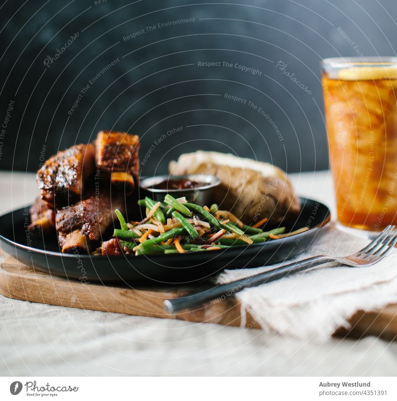 Ribs dinner meal with fancy green beans and potato on a farmhouse country linen tablecloth american background baked baked potato barbecue barbecued barbeque