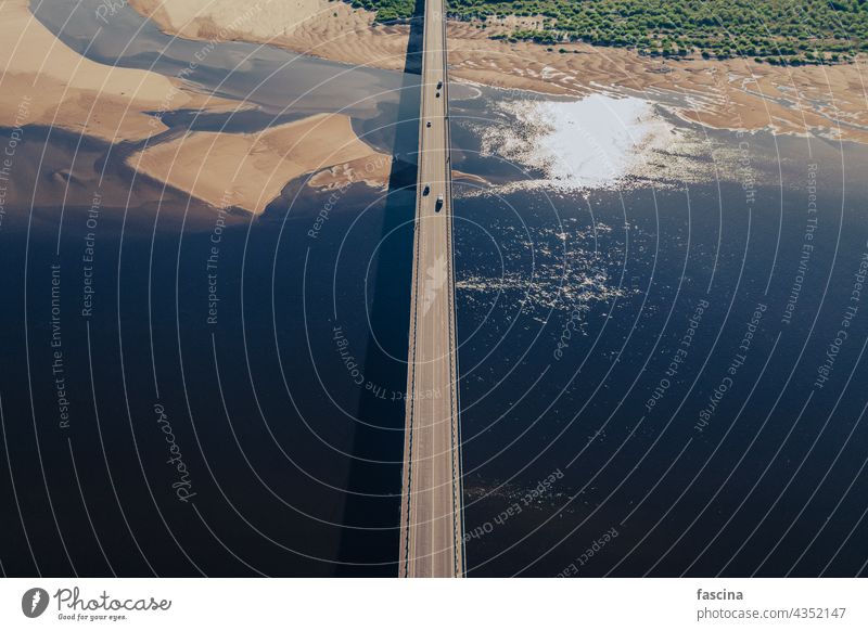 Aerial view of bridge over river in sunset light aerial cars amazing birds eye blue water surface sand islands dunes meandering green shrubs travel road