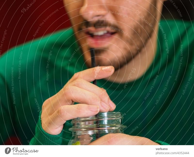young person drinking a cocktail on a jar with a straw man caucasian mouth glass juice beverage fruit summer cold background sweet lemonade fresh healthy mint