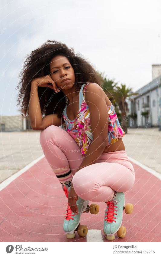portrait of beautiful young afro woman on roller skates with urban background skater curly black look hair closeup latin eyes curls hispanic hairstyle beauty
