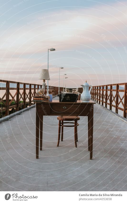 Old desk. Work table on a pier. Working with a beautiful landscape. Desk with books, clock, lamp. Digital Nomad. background business chair coffee countryside