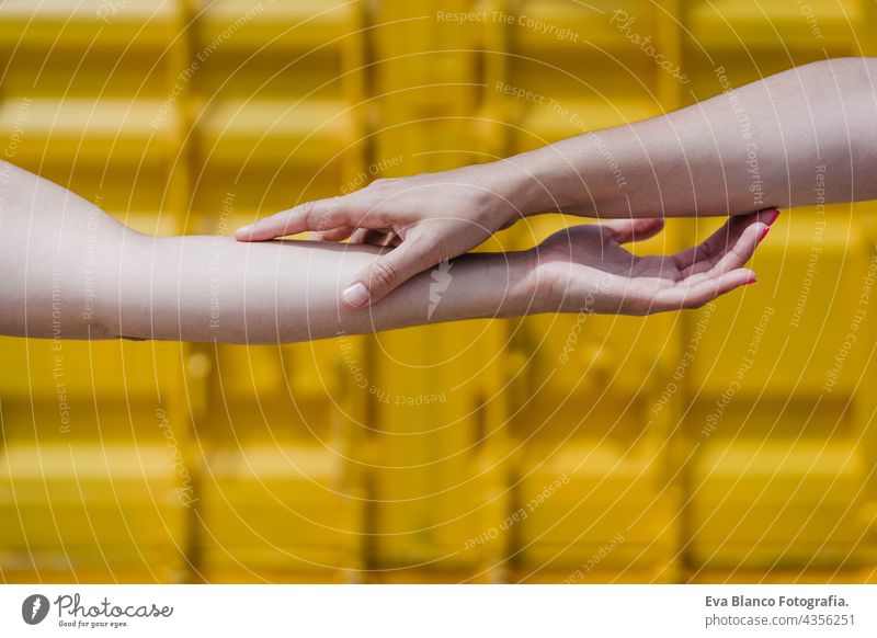 close up of lesbian couple holding hands in front of yellow background. Love is love . LGBTI concept unrecognizable happy caucasian women friends together