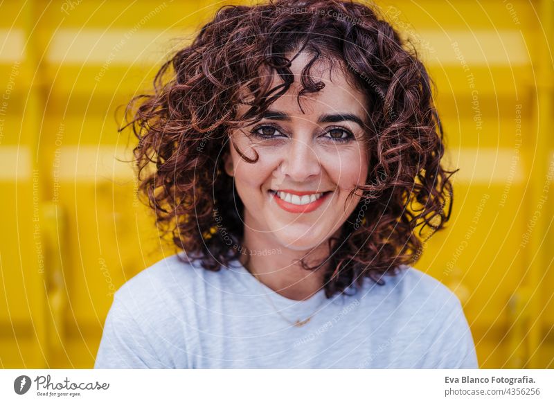happy caucasian woman with curly hair over yellow background. summer time. Outdoors lifestyle brunette smiling outdoors city carefree smile town alicante spain