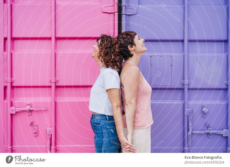 happy lesbian couple smiling and holding hands over pink and purple background. Love is love. LGTBI concept hug together women homosexual summer sunset young