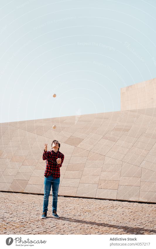 Man juggling clubs near geometric building man juggle trick perform architecture contemporary geometry entertain talent art skill activity practice male modern