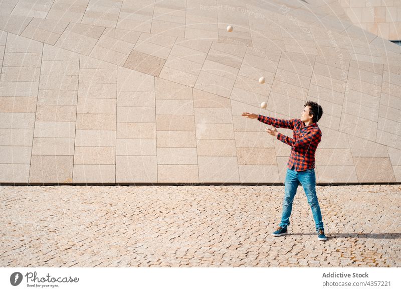 Young man juggling balls near modern building juggle trick perform architecture contemporary geometry entertain talent art skill activity practice male young