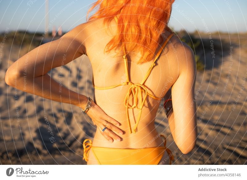 Anonymous woman standing on beach bikini fit back apply suntan lotion summer sunscreen vacation sea travel back view holiday pale anonymous young redhead slim