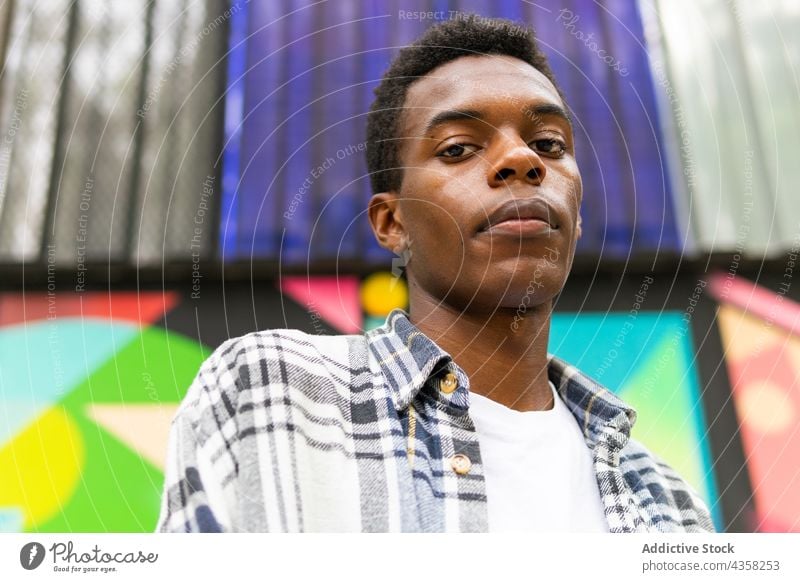 Black man looking at camera on colorful background carefree dreamy street city style serene tranquil enjoy male ethnic black african american wall calm