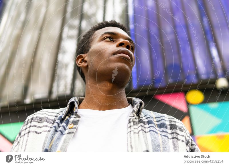 Black man looking away on colorful background carefree dreamy street city style serene tranquil enjoy male ethnic black african american wall calm appearance