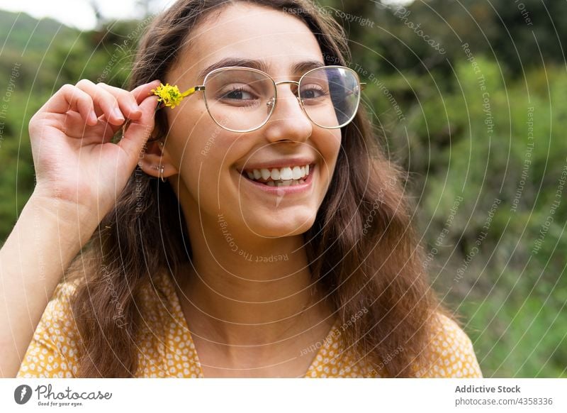 Smiling woman with flower in hair in countryside summer smile nature bloom wildflower cheerful female happy yellow field charming glad enjoy pleasant natural
