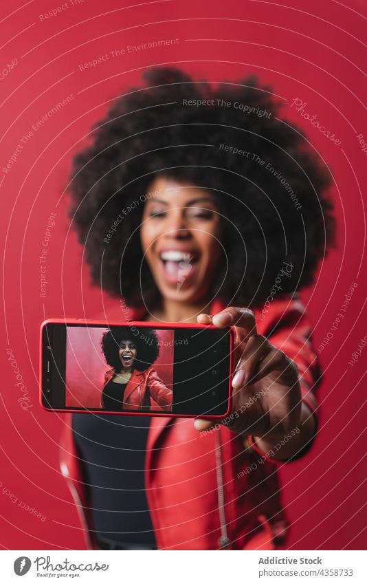 Black woman taking selfie on smartphone in studio black afro self portrait red color photo hairstyle memory female african american ethnic device take photo