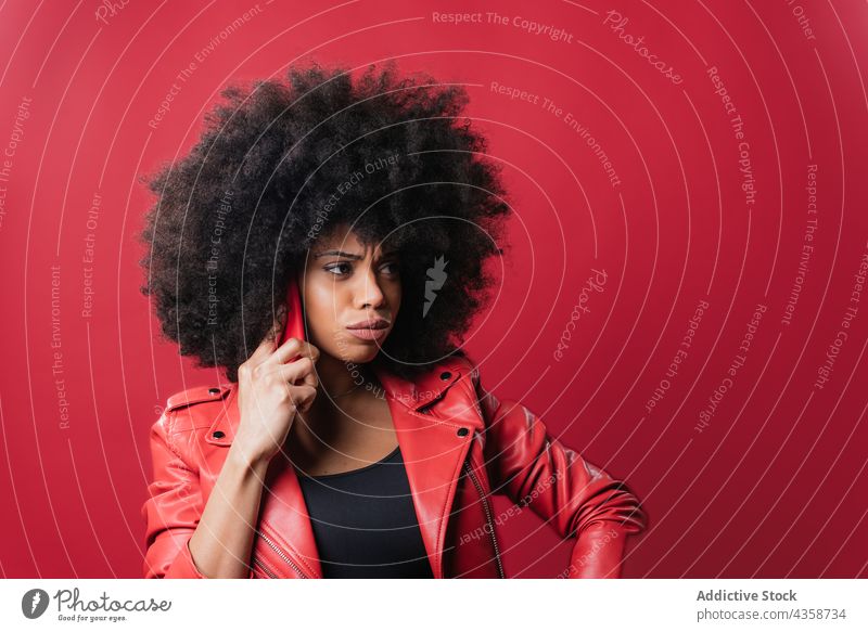 Black woman with pouting lips browsing smartphone in studio black afro using excited message red color bright female african american ethnic hairstyle content