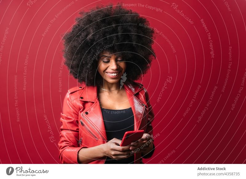 Black woman browsing smartphone in studio black afro using excited message red color bright female african american ethnic hairstyle content choos pick interest