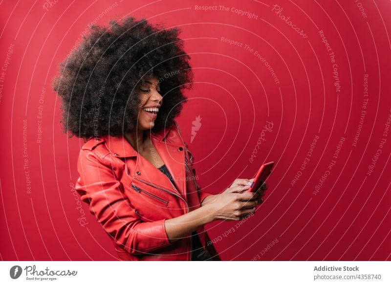 Black woman browsing smartphone in studio black afro using excited message red color bright female african american ethnic hairstyle content choos pick interest
