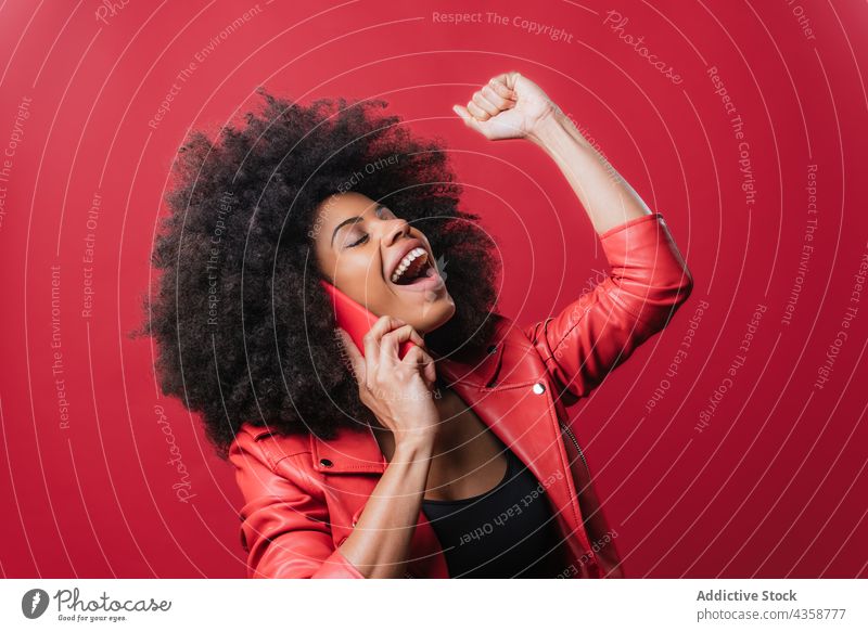Happy black woman talking on smartphone and celebrating victory celebrate success speak excited achieve goal female african american ethnic cheerful clench fist