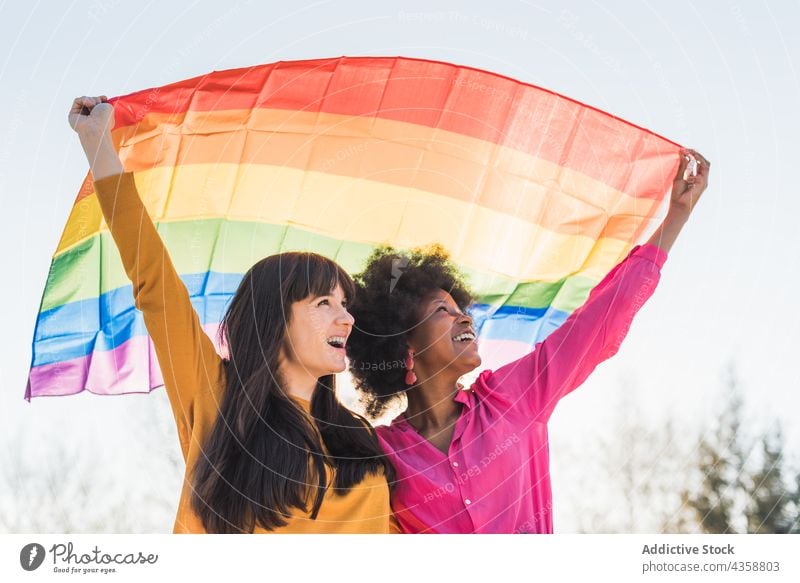 Positive multiethnic lesbian women with LGBT flag in city lgbt homosexual rainbow pride equal couple tolerance female multiracial diverse black african american