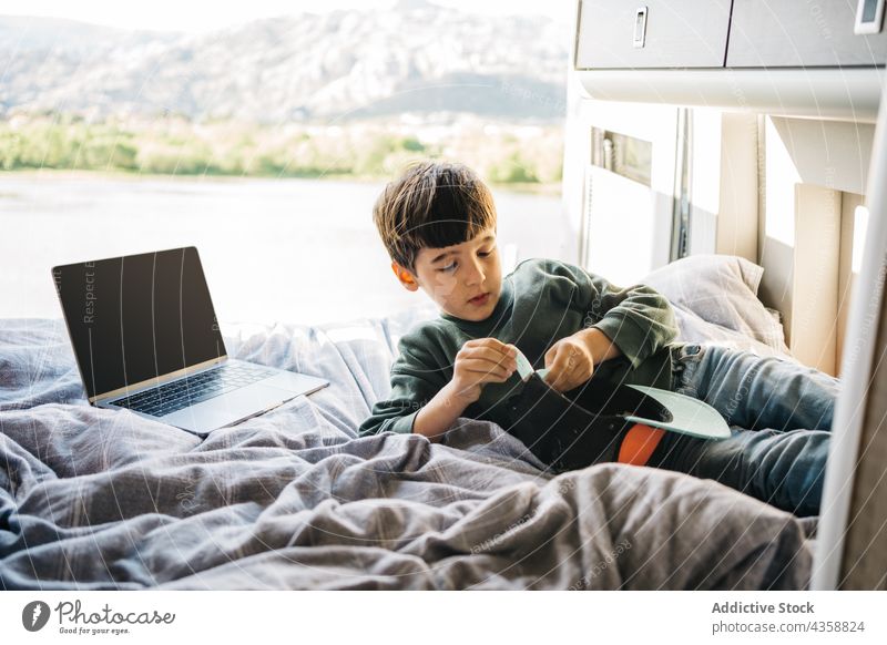 Little boy relaxing inside a motorhome while lying on the bed bedroom indoors relaxation laptop lying down cap vacations child portrait motor home innocence
