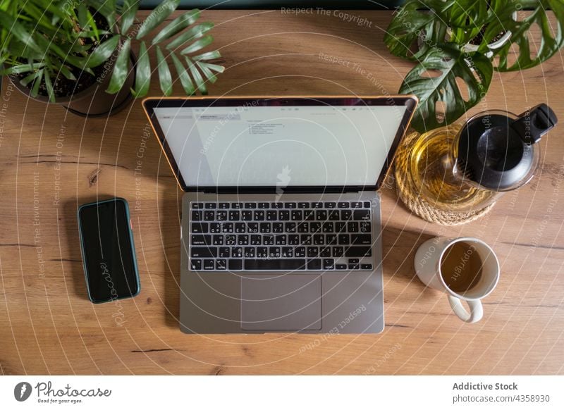 Laptop and smartphone on wooden table at home laptop freelance workplace tea gadget device netbook telework cup workspace desk modern internet computer drink