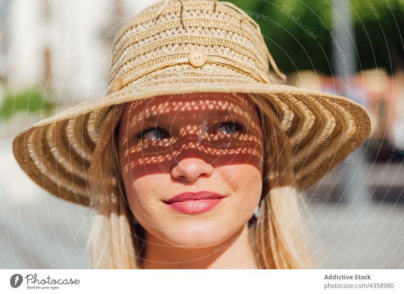 Woman in straw hat on sunny day in city woman summer sunhat charming summertime style street female sunlight trendy holiday carefree lady young feminine blond