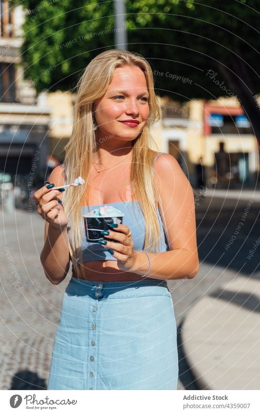 Woman eating ice cream on street in summer woman city refreshment cold tasty dessert delicious female blonde young sweet stand food pretty frozen yummy treat
