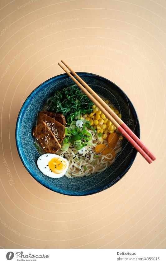Top down view of a bowl of vegetarian ramen noodle soup with tofu and boiled egg ramen noodles japanese food no people background chopsticks spring onion