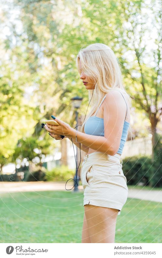 Woman listening to music in earphones in park woman summer song smartphone entertain serene female enjoy melody gadget device audio carefree tune sound calm