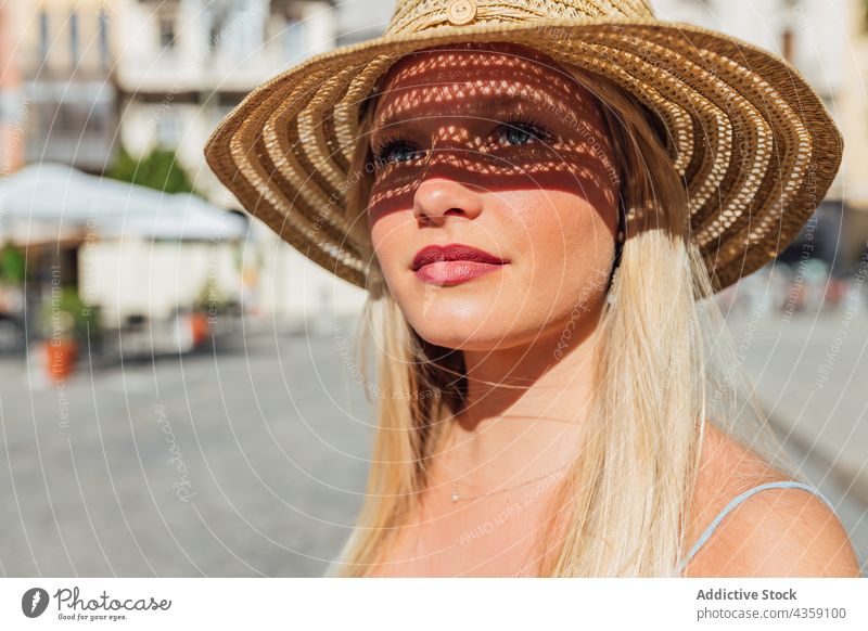 Woman in straw hat on sunny day in city woman summer sunhat charming summertime style street female sunlight trendy holiday carefree lady young feminine blond