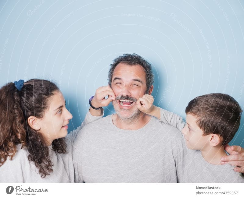 father and two children doing funny faces, fathers day concept family siblings daughter son teenager male female 3 people together isolated blue background love