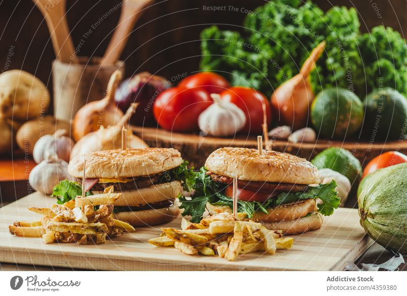 Tasty hamburgers served with French fries on table fast food appetizing vegetable cutlet french fries junk food meal tasty cutting board potato meat delicious