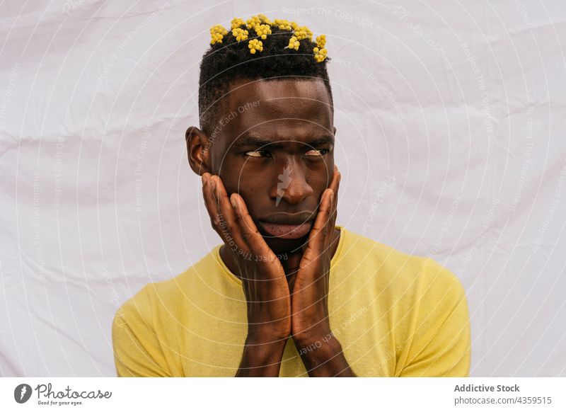Serious black man with yellow flowers in hair wildflower color serious frown trendy bloom male ethnic african american style model pensive calm fashion
