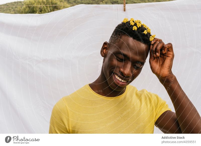 Happy black man with yellow flowers in hair wildflower color trendy bloom male ethnic african american style model fashion appearance handsome cool