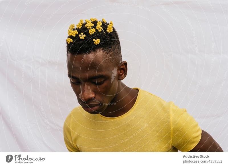 Serious black man with yellow flowers in hair wildflower color serious trendy bloom male ethnic emotionless african american style model unemotional pensive