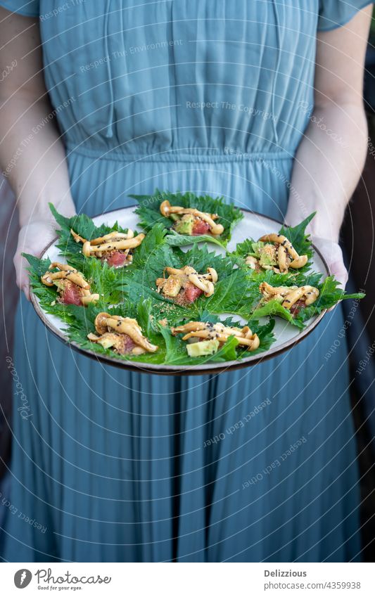 A woman in a blue dress holding a plate of vegan Asian appetizers hands arms food asian vegetarian tasty delicious beautiful present raw shiso perilla mushrooms