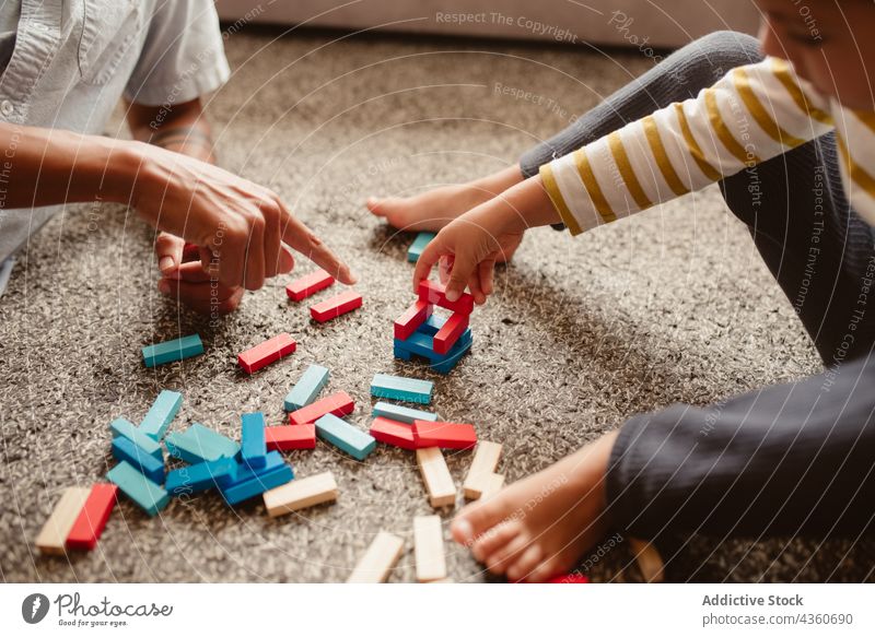 Anonymous father and son playing with construction pieces in the dining room child block brick together toy boy family man childhood education game smile build