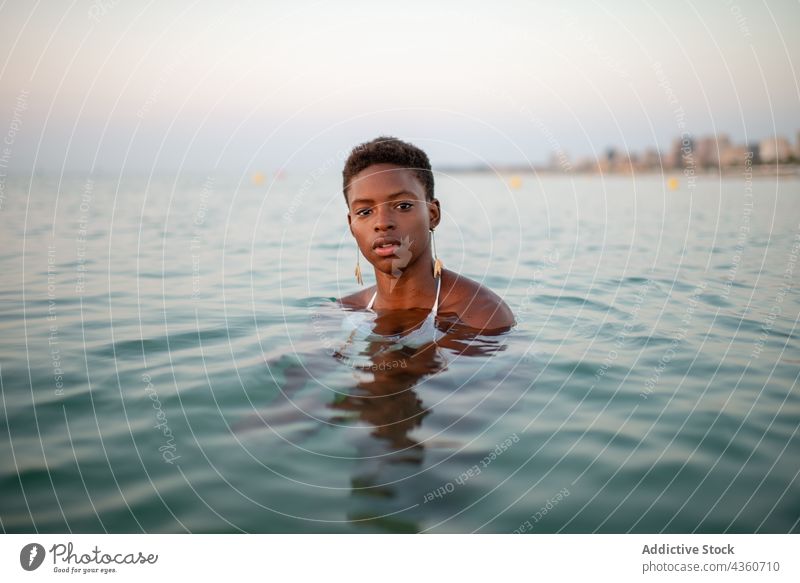 Black woman with short hair in the sea water sunset ripple sundown evening summer female ethnic black african american tranquil beautiful relax carefree holiday