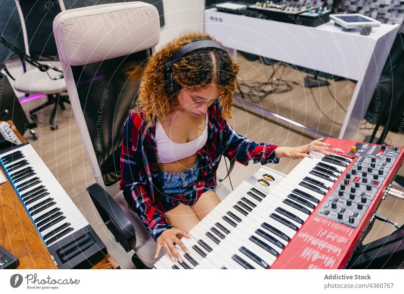Black vocalist playing synthesizer while singing into microphone in studio song headset woman using gadget device singer music headphones instrument musical