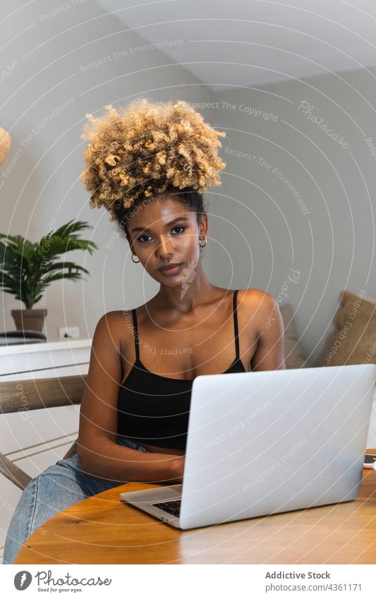 Black woman with laptop sitting on chair during breakfast watch work using remote online busy morning female device browsing gadget home connection serious