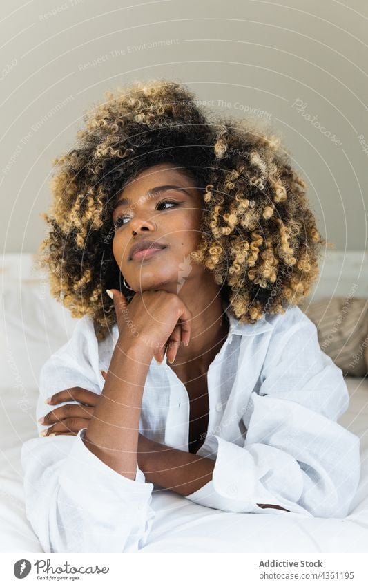 Black woman lying on bed in bedroom enjoy rest positive comfort relax morning female happy home glad carefree hairstyle ethnic black african american pleasant