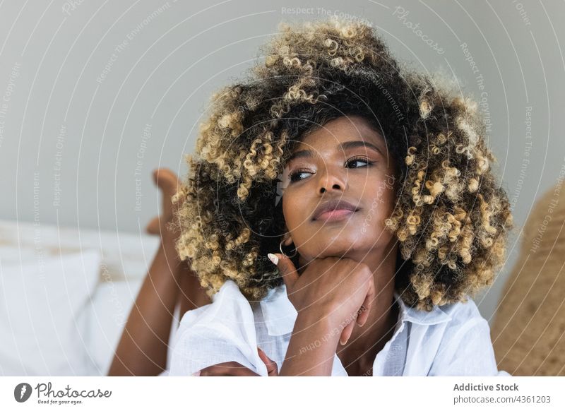 Thoughtful black woman lying on bed in bedroom enjoy rest positive comfort relax morning female happy home glad carefree hairstyle ethnic african american
