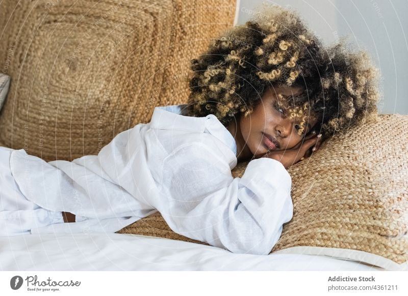 Thoughtful black woman lying on bed in bedroom enjoy rest positive comfort relax morning female happy home glad carefree hairstyle ethnic african american