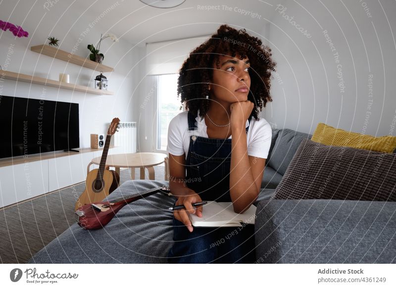 Black musician composing music at home woman compose thoughtful notebook pensive creative notepad female ethnic black african american mandolin guitar acoustic
