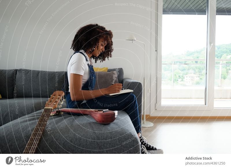 Black musician composing music at home woman compose thoughtful notebook pensive creative notepad female ethnic black african american mandolin guitar acoustic