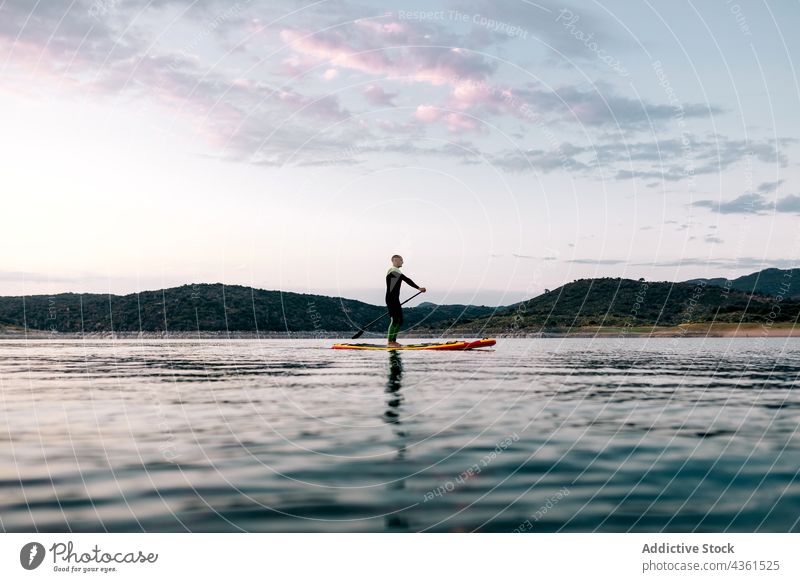 Unrecognizable man floating on paddleboard in sea surfer sup board sunset summer male water activity ocean evening vacation calm recreation surfboard sport