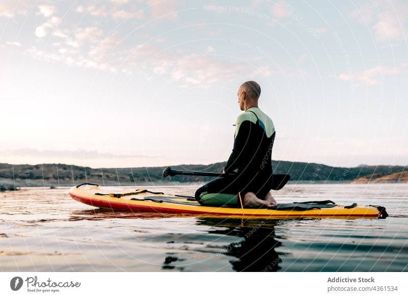 Man practicing yoga on SUP board in sea man paddleboard meditate sup board practice thunderbolt pose namaste evening male surfer water asana sunset calm healthy