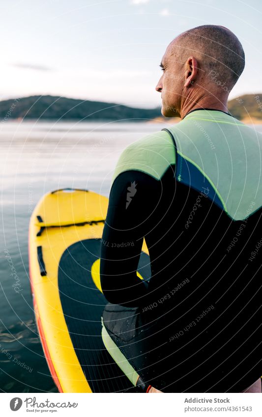 Man on paddle board floating on lake man paddleboard sport kneel activity practice male active sporty adult water sports hobby recreation swim lifestyle energy
