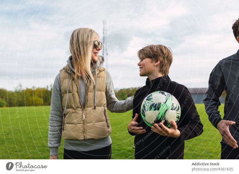 Sporty family gathering in field for playing football player sport sporty weekend spend time woman soccer game activity grass green together walk son female