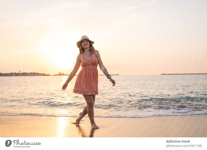 Young woman having fun on beach at sunset summer sea happy carefree style vacation traveler female barefoot sand holiday wave enjoy shore tourist ocean freedom