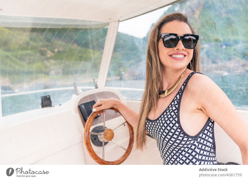Side view of a young girl driving a yacht woman vacation summer luxury boat sea person happy attractive water ship female sailboat travel sailing sunglasses